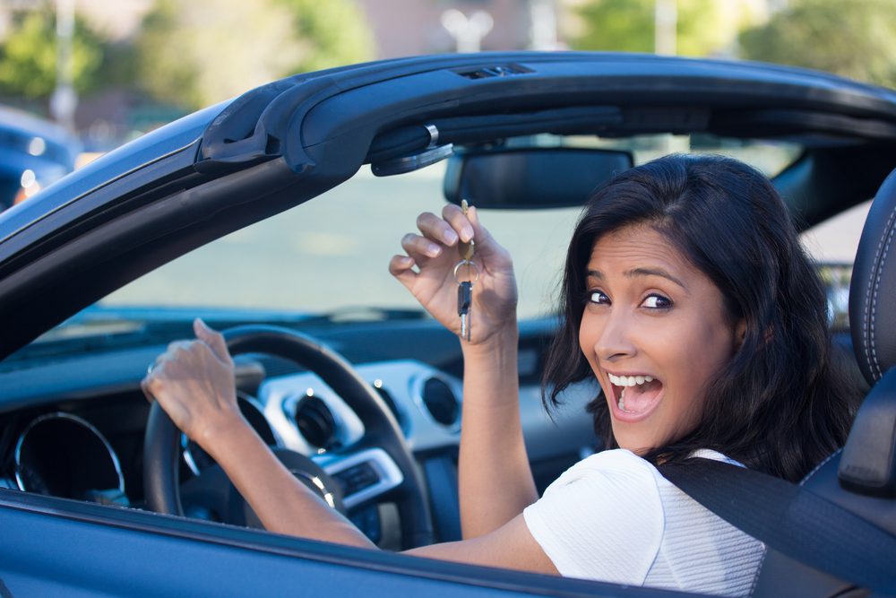 Happy woman driving new car.