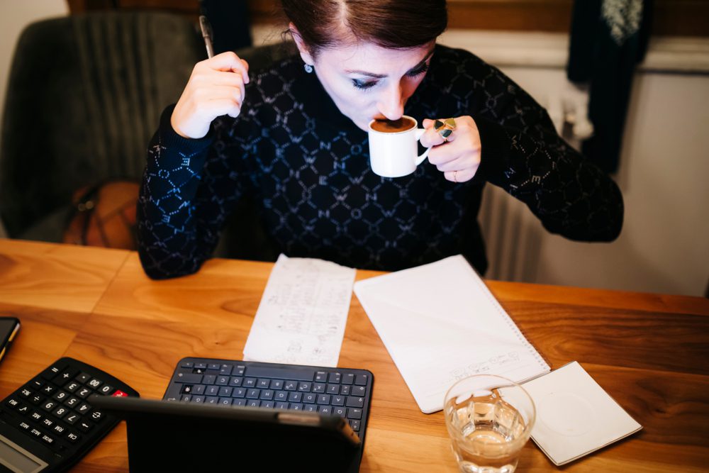 Woman working overtime and drinking coffee.
