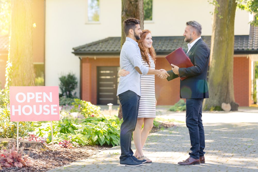 Agent welcoming a couple at an open house.