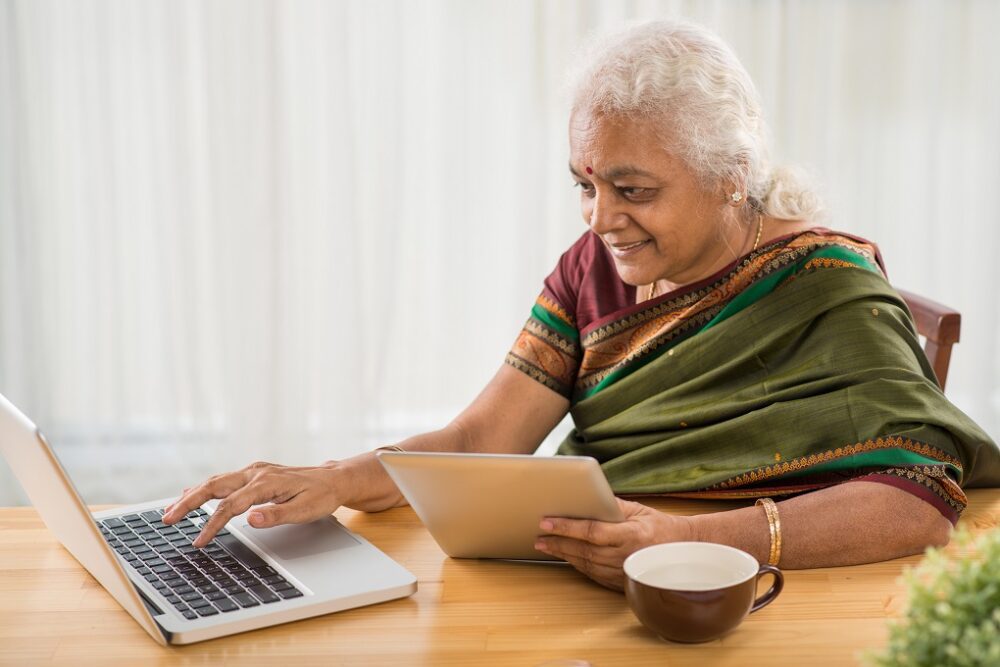 Senior Indian woman learning how to use digital tablet and laptop