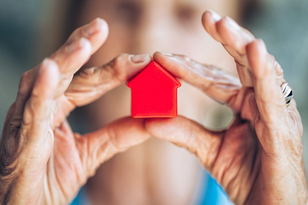 Elderly woman holding a small house in her hands