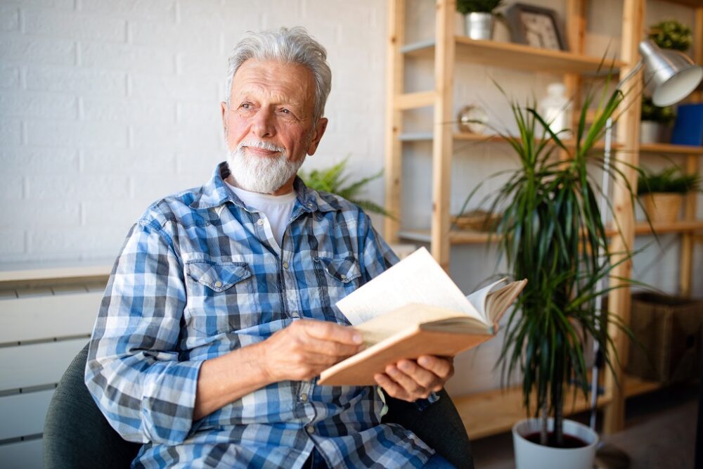Happy mature man reading book at home