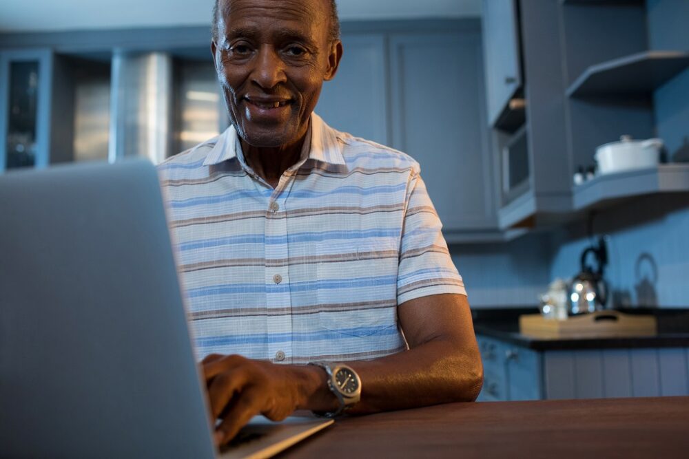 Portrait of senior man using laptop while sitting home