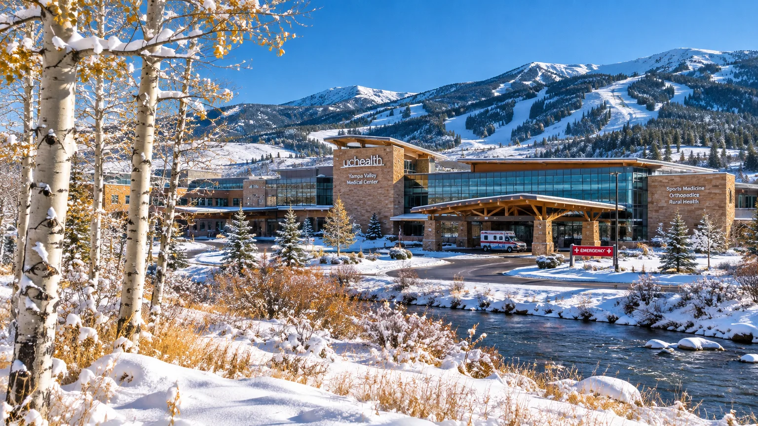 Modern UCHealth medical center beside a snowy river and aspen trees, with snow-covered ski slopes rising in the background.